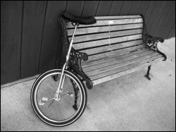 Unicycle leaning against park bench